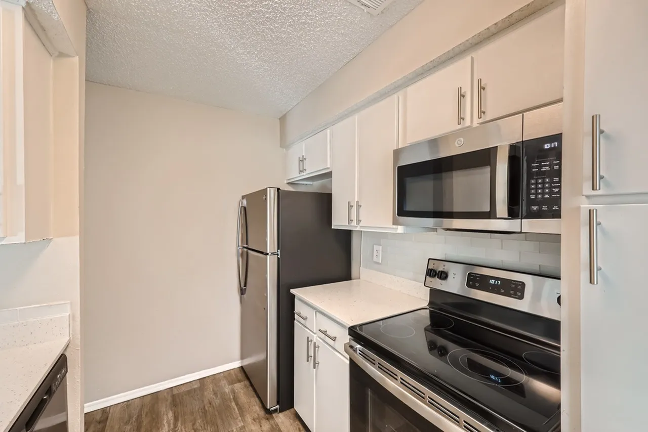 Kitchen, white shaker cabinetry, stainless steel appliances, wood-style plank flooring