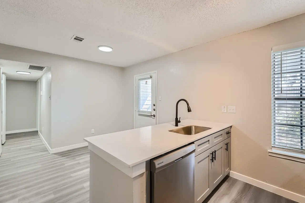 Kitchen, white quartz countertops, white cabinetry, black faucet, stainless appliances, wood-style plank flooring