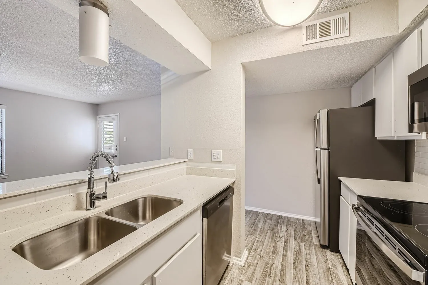 Kitchen, white cabinetry, quartz countertops, stainless appliances, wood-style plank flooring