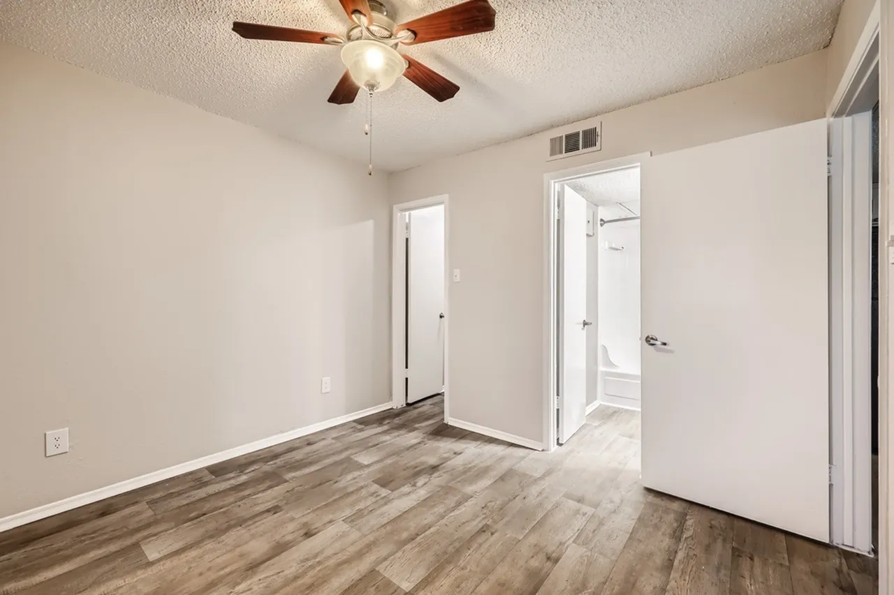 Bedroom, wood-style plank flooring, ceiling fan with light fixture, white doors