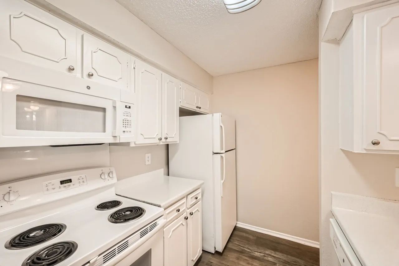 Kitchen, white shaker cabinetry, gray countertops, white appliances, wood-style plank flooring