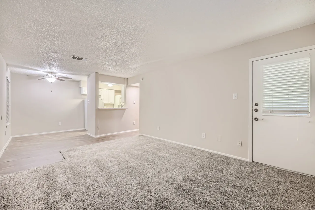 Living room with gray carpet, ceiling fan, exit door with blinds