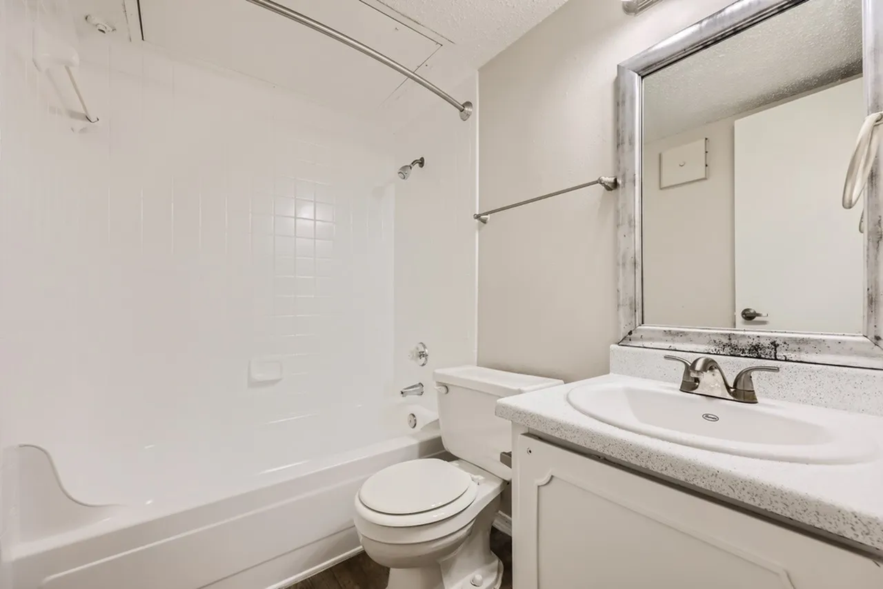 Bathroom, white vanity, gray countertop, framed mirror, white subway tile, toilet