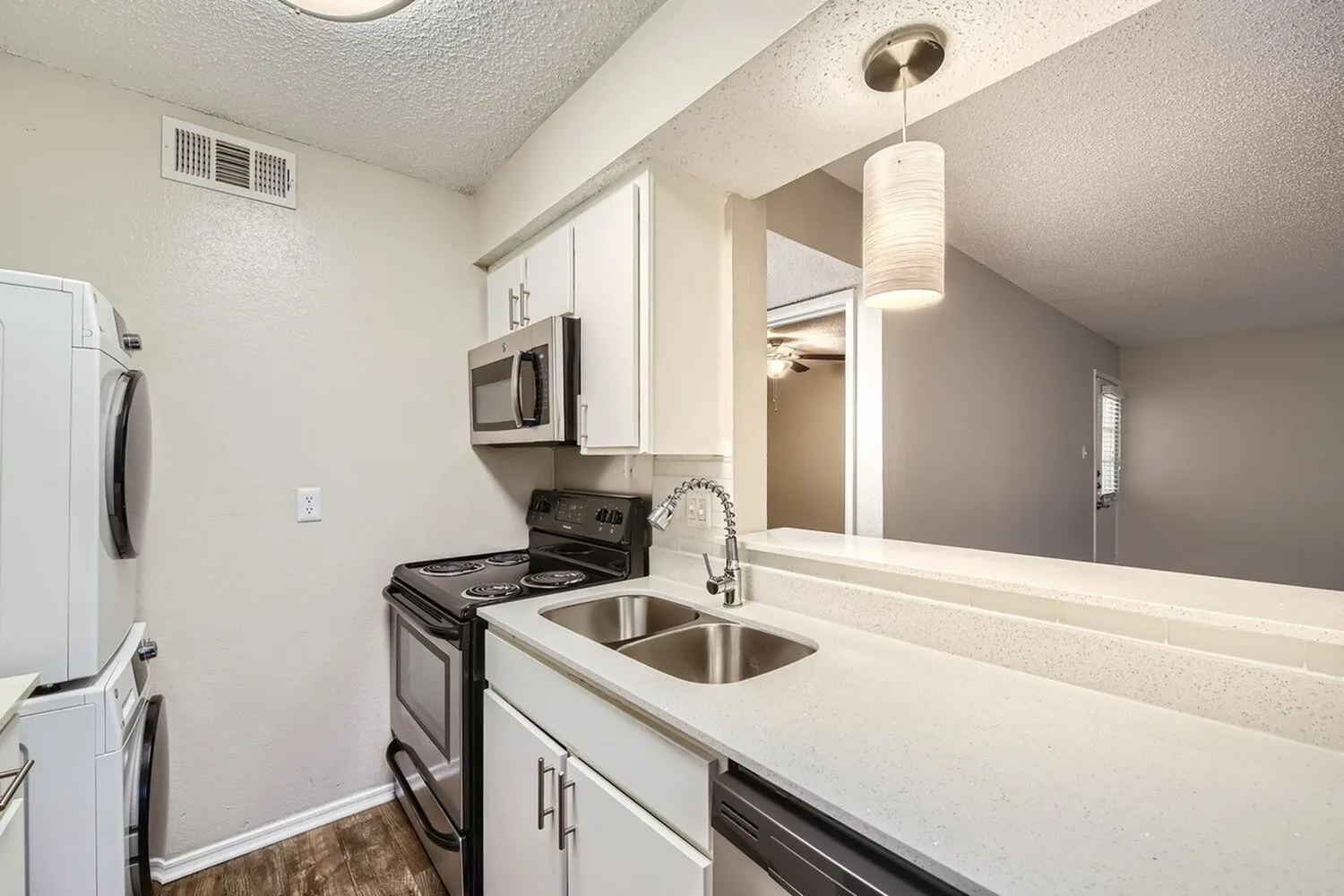 Kitchen, white cabinetry, quartz countertops, stainless steel double sink, black appliances, wood-style plank flooring