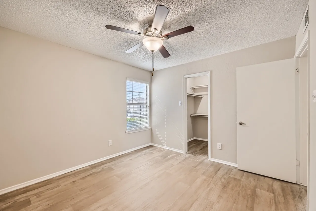 Bedroom, wood-style plank flooring, ceiling fan with light, walk-in closet, window