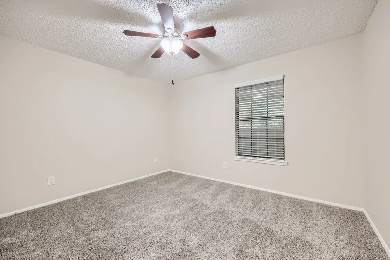 Bedroom, gray carpet flooring, ceiling fan with light, window with shutters