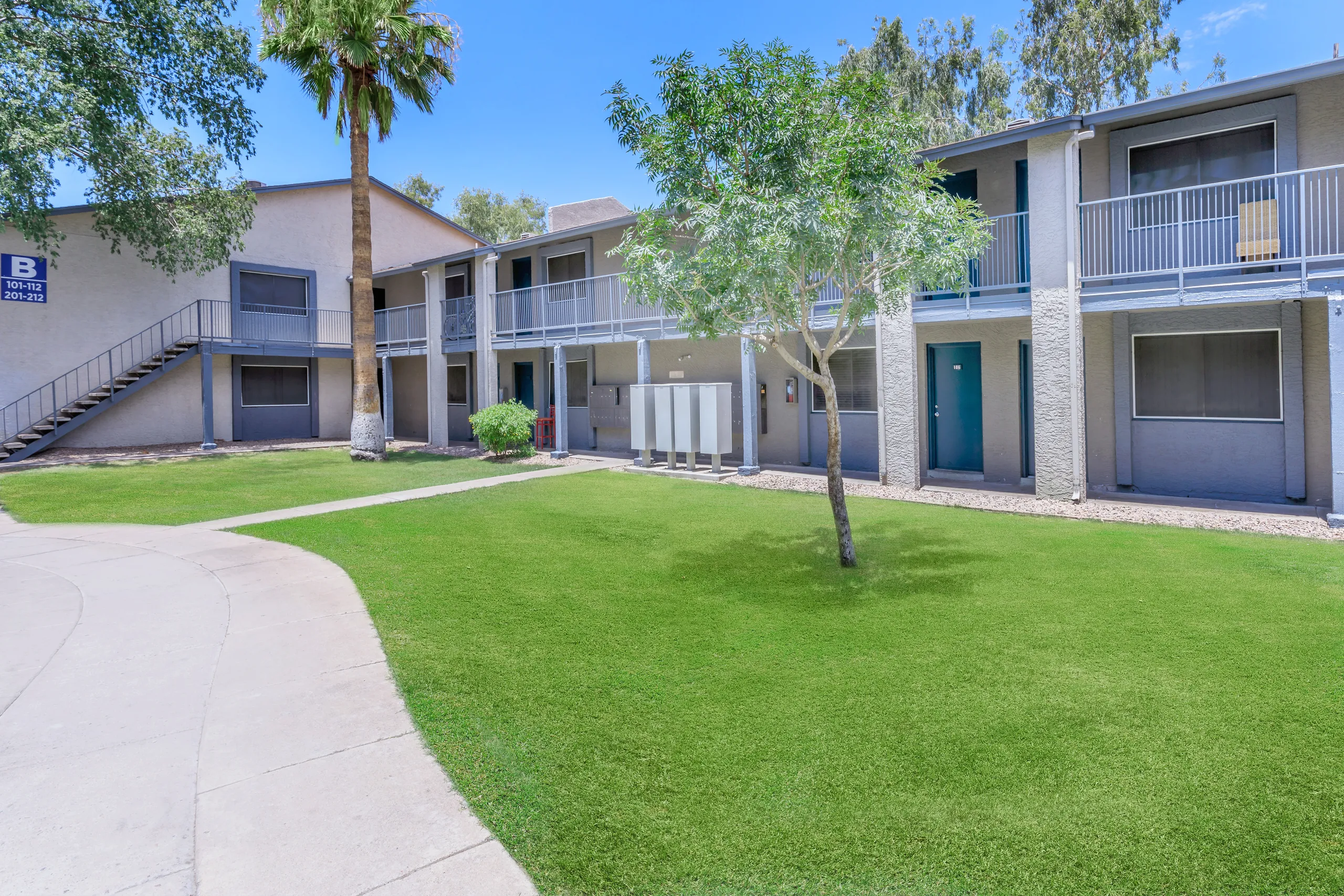 Community courtyard with mailboxes, palm trees, and green lawn