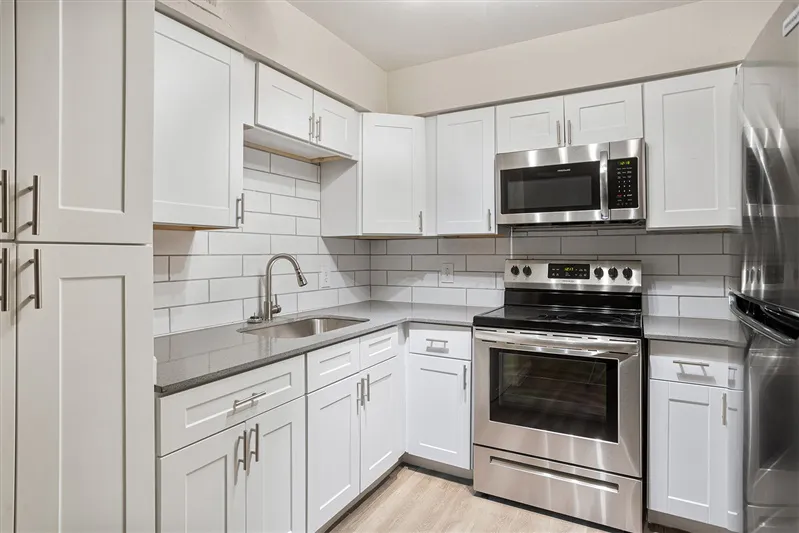 White kitchen with stainless steel appliances and subway tile backsplash