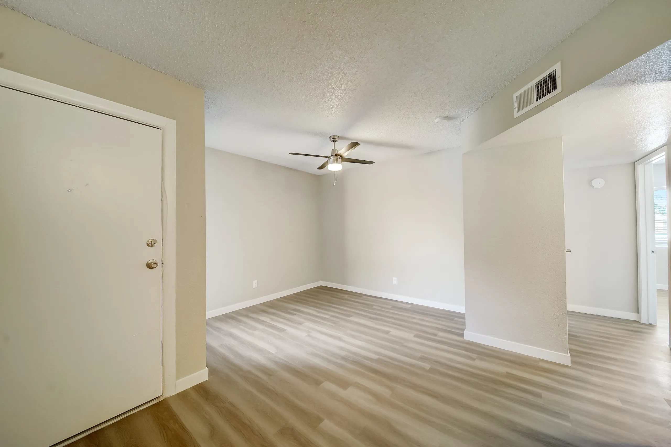 Open living area with entry door and view into hallway
