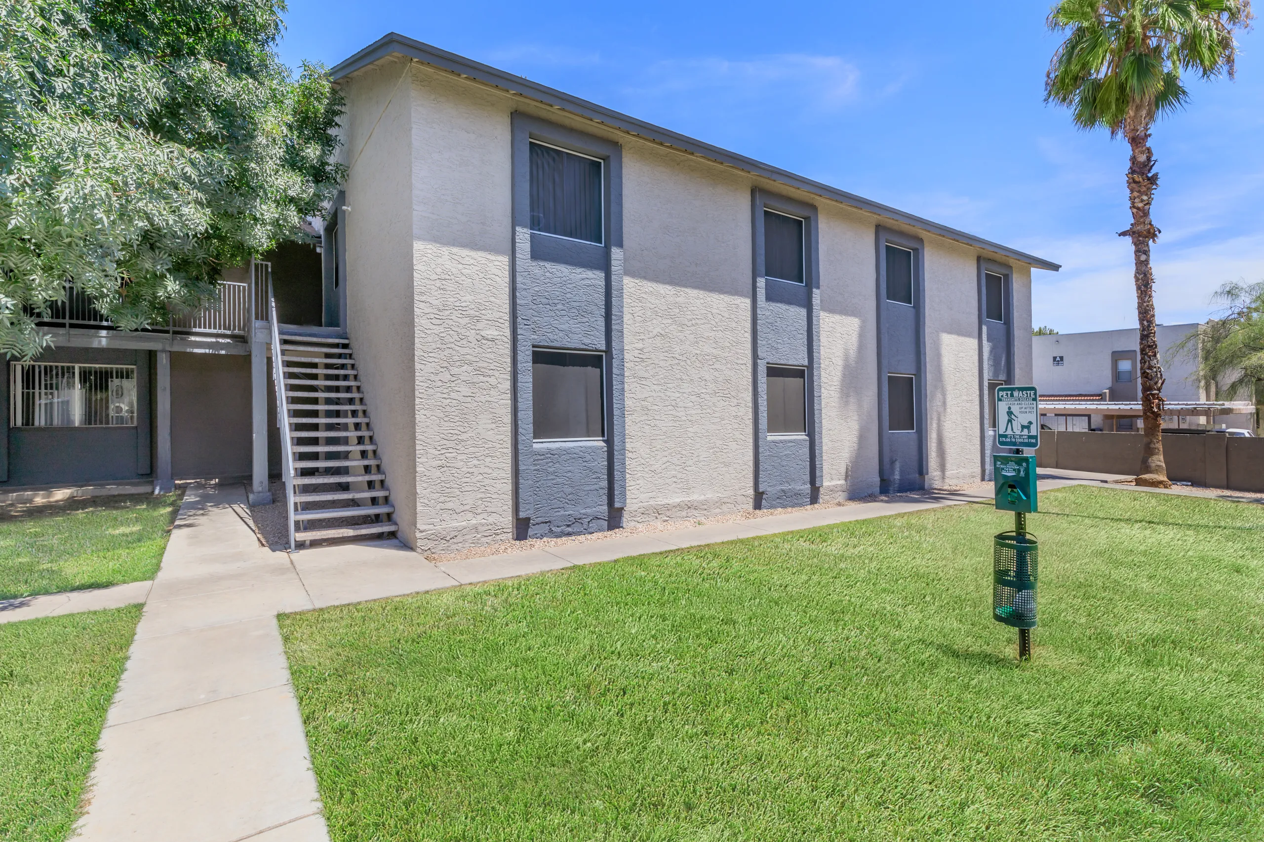 Two-story apartment building exterior with staircase and landscaping