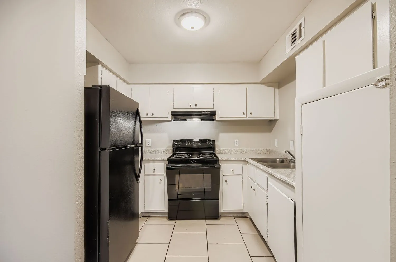 Kitchen with black appliances and white cabinetry