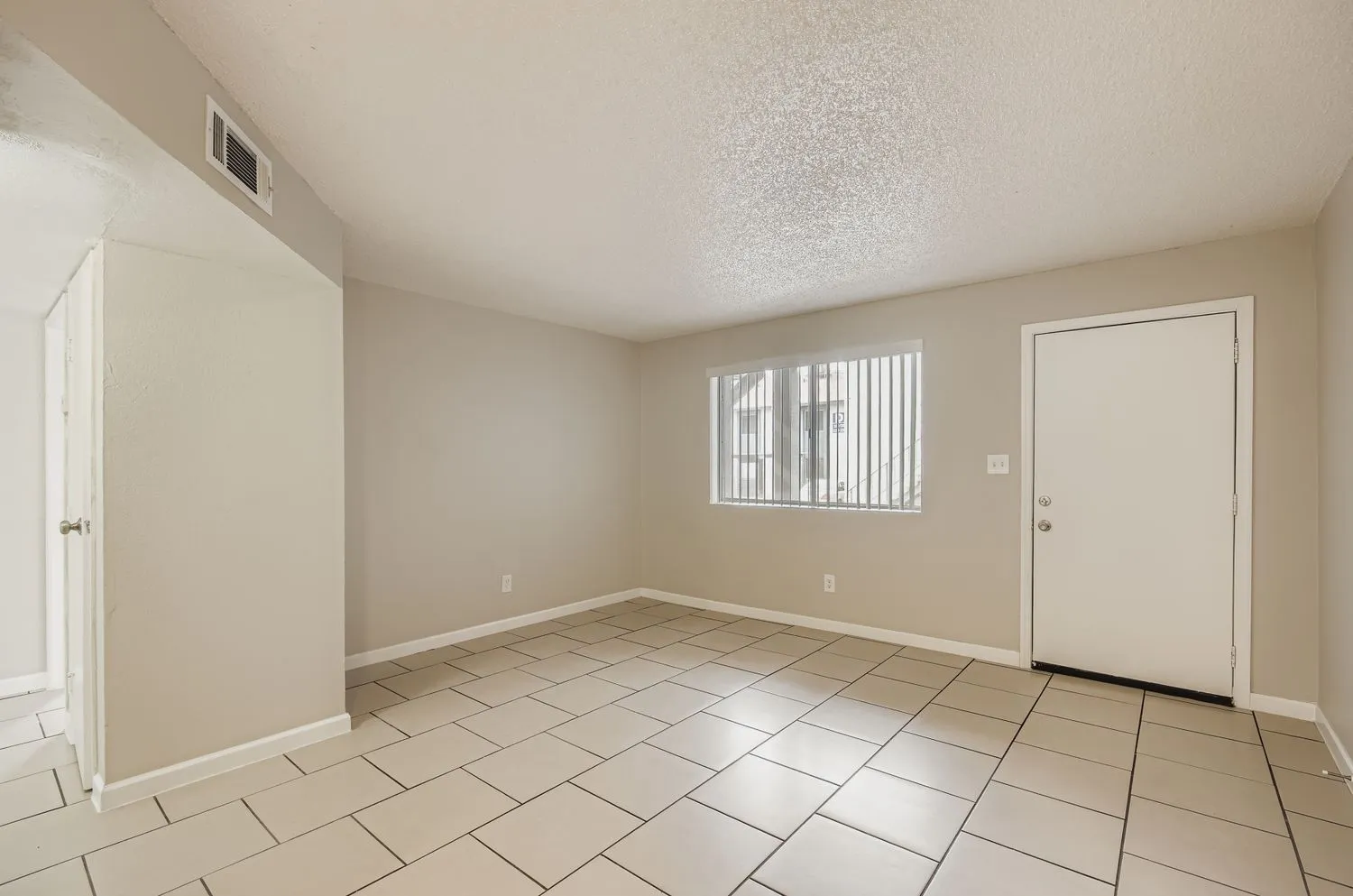 Living room with tile flooring, entry door, and window