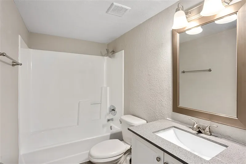 Renovated bathroom with granite-style vanity and tub/shower combo