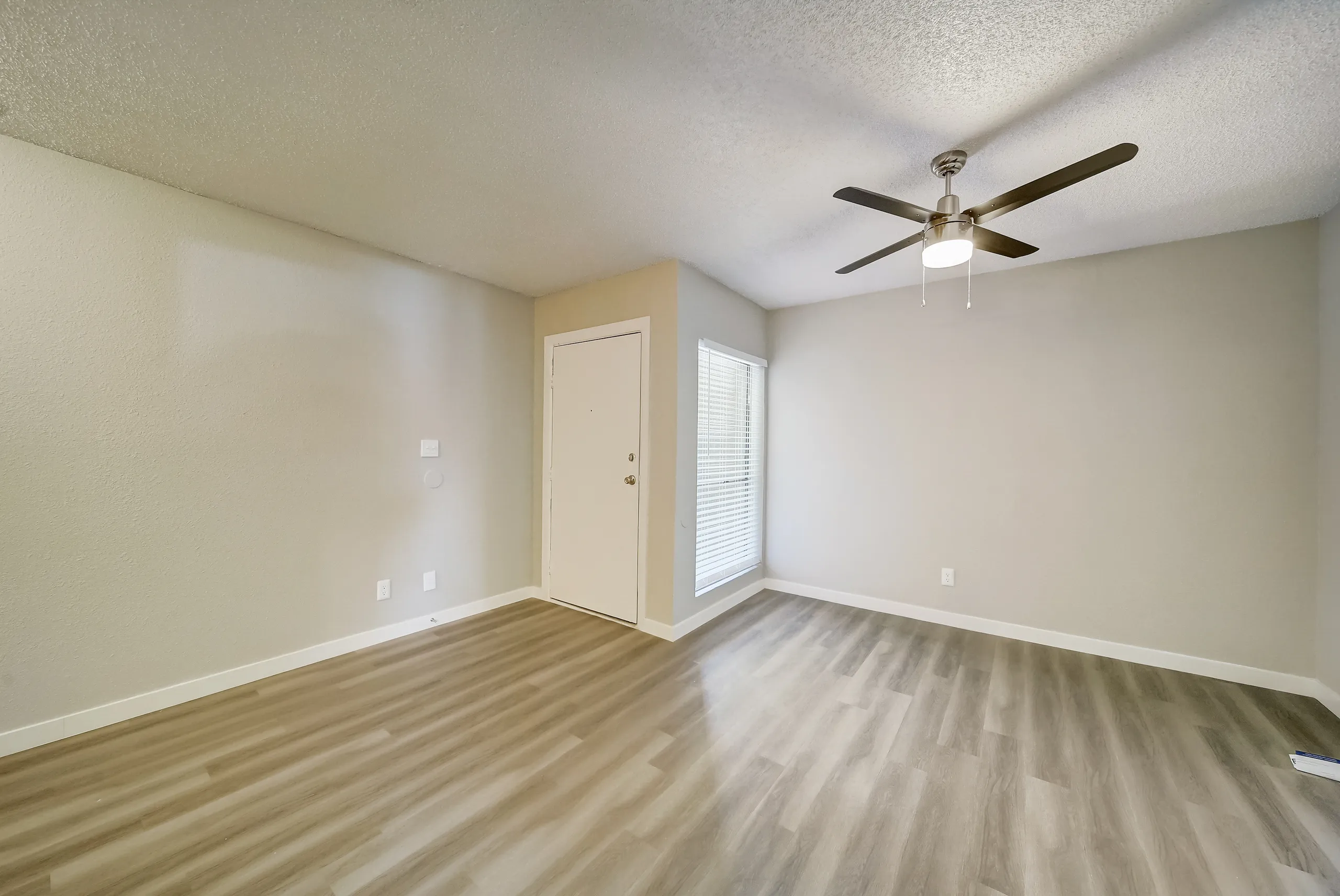 Living room with ceiling fan, entry door, and window