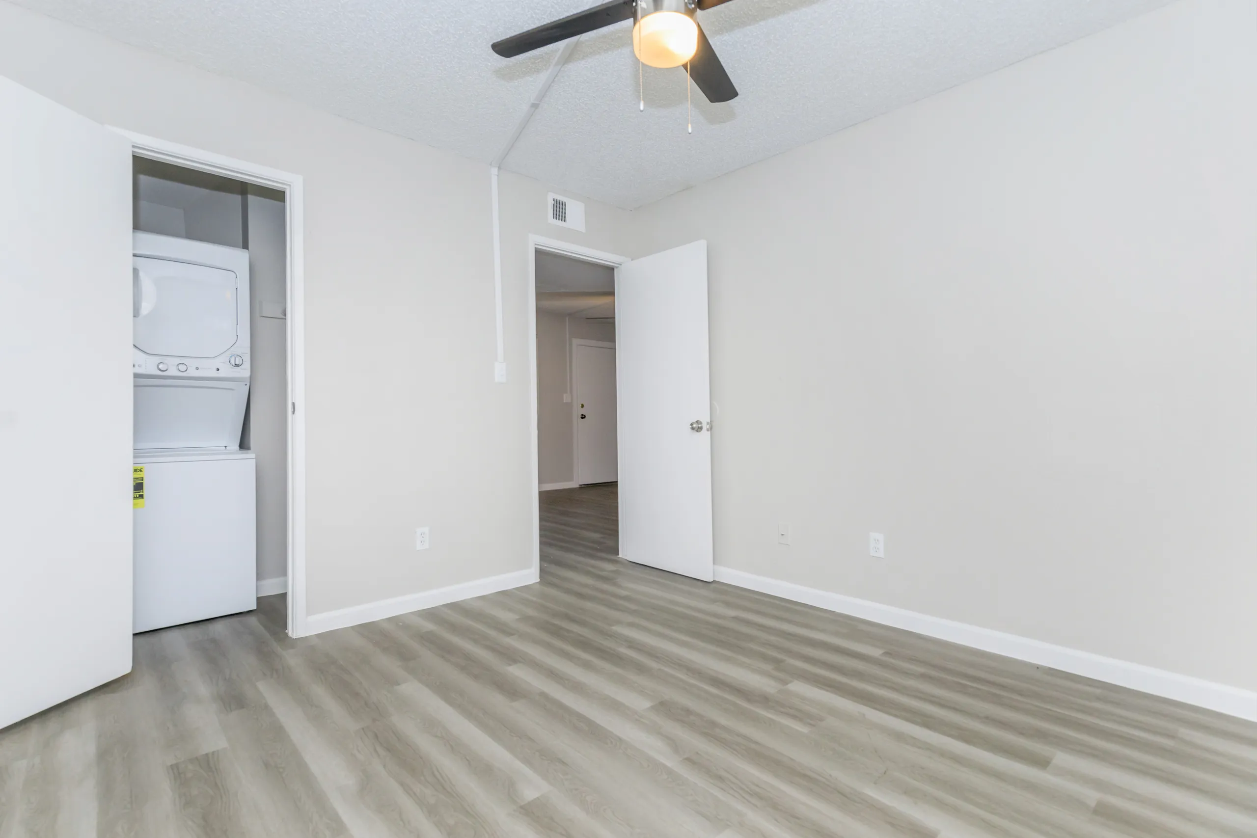Bedroom with ceiling fan and in-unit stacked washer and dryer