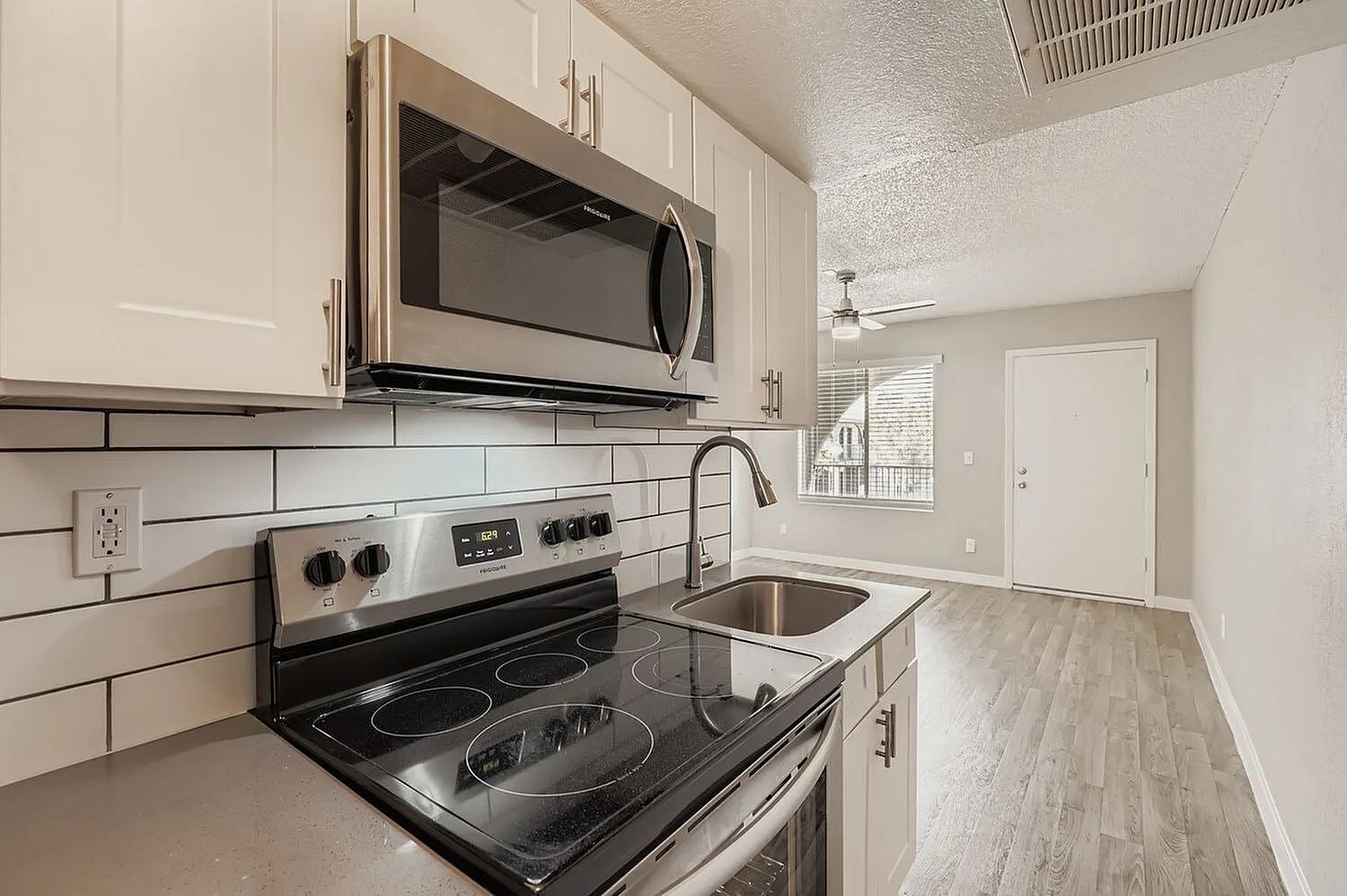 Kitchen, white shaker cabinetry, subway tile backsplash, stainless appliances, wood-style plank flooring
