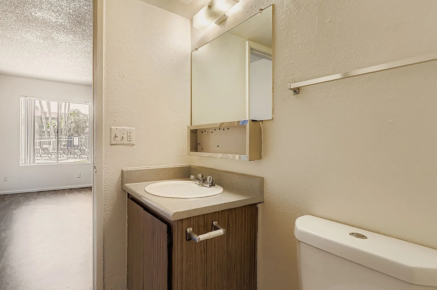 Bathroom, wood-style vanity cabinet, round white sink, mirror cabinet, towel bar