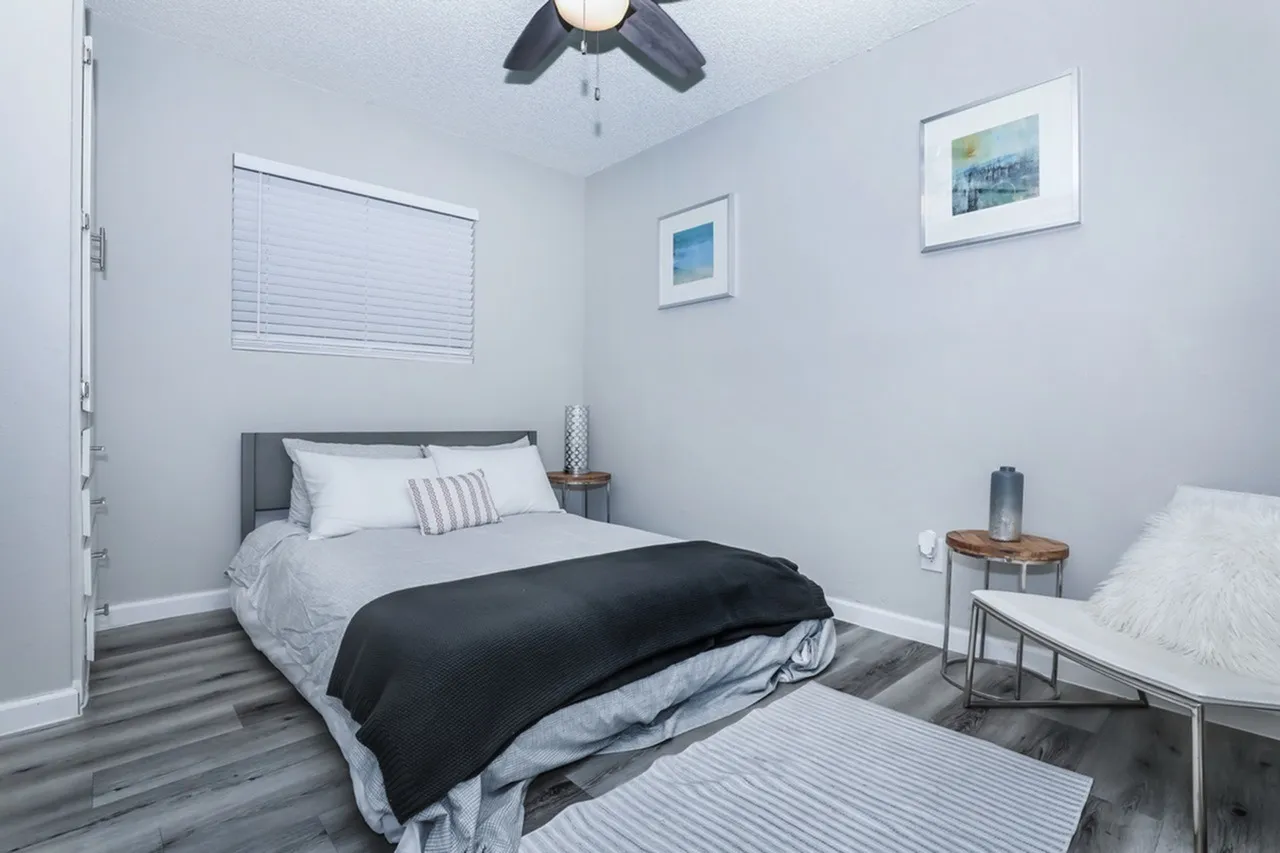 Bedroom, wood-style plank flooring, black ceiling fan, framed wall art