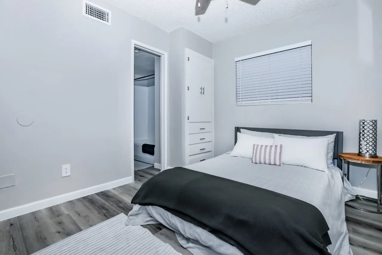 Bedroom, wood-style plank flooring, platform bed with black comforter, built-in closet organizer