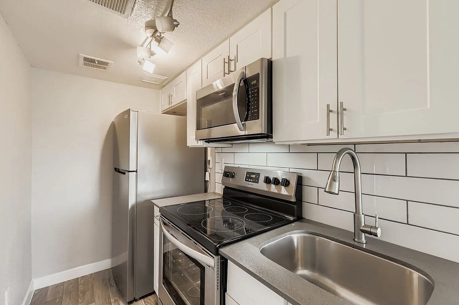 Kitchen, white shaker cabinetry, gray quartz countertops, stainless steel appliances, subway tile backsplash