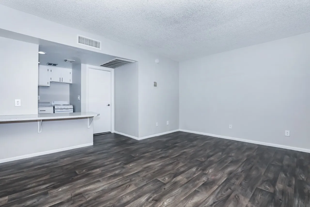 Studio apartment, wood-style plank flooring, white walls, kitchenette with white cabinetry