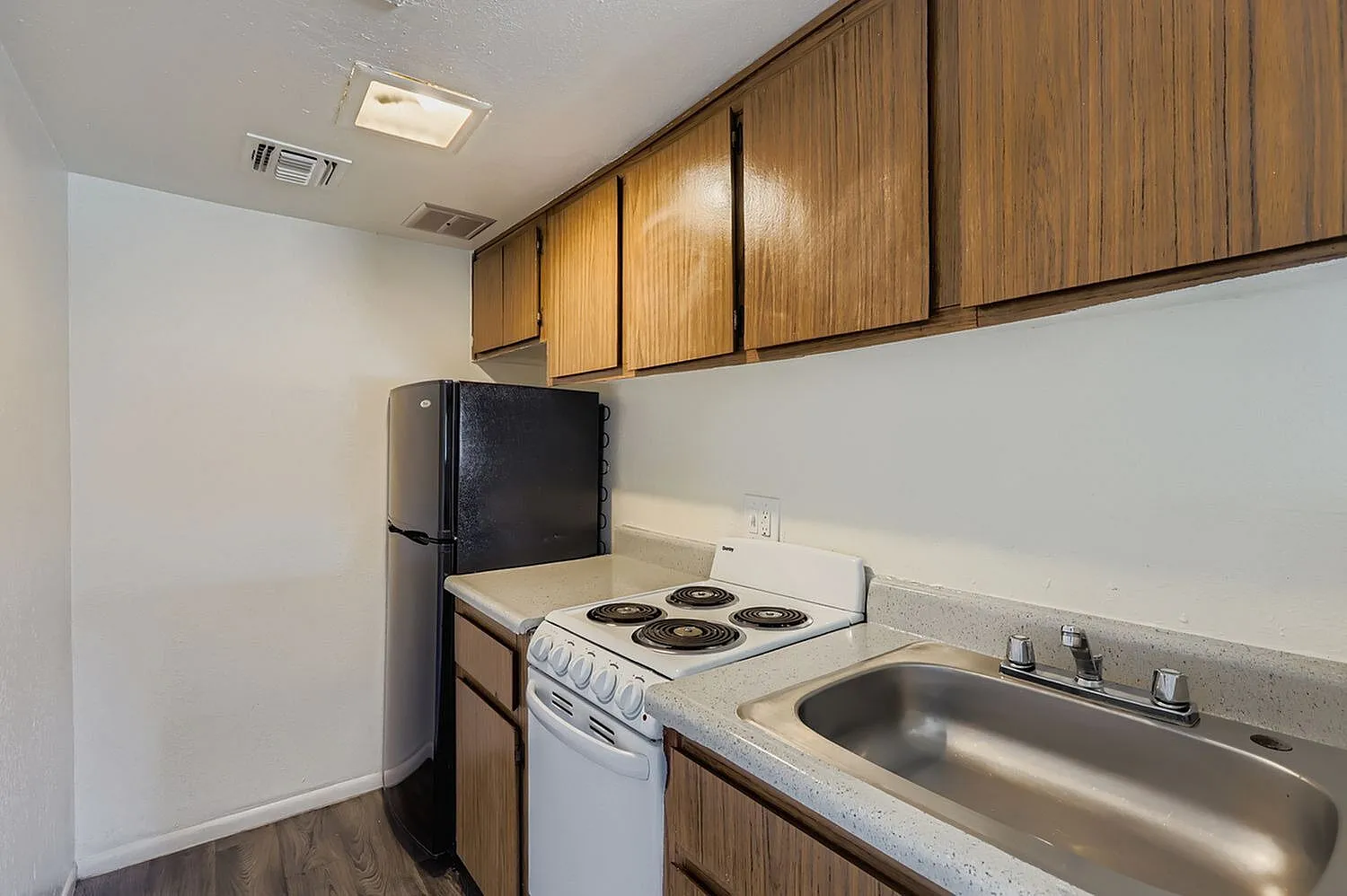 Kitchen, wood cabinetry, laminate countertops, black refrigerator, electric range, stainless sink