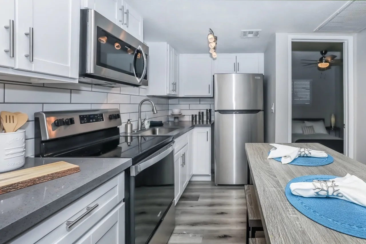 Kitchen, white shaker cabinetry, black quartz countertops, stainless appliances, wood-style plank flooring