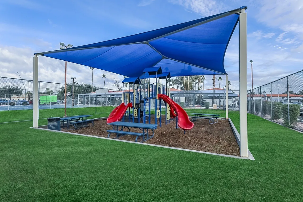 Playground, blue shade sails, red dual slides, climbing structure, wood mulch surface, Mesa