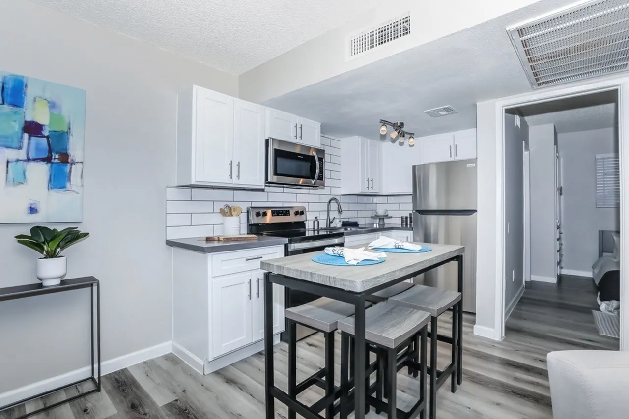 Kitchen, white shaker cabinetry, subway tile backsplash, stainless appliances, black countertop, wood-style plank flooring