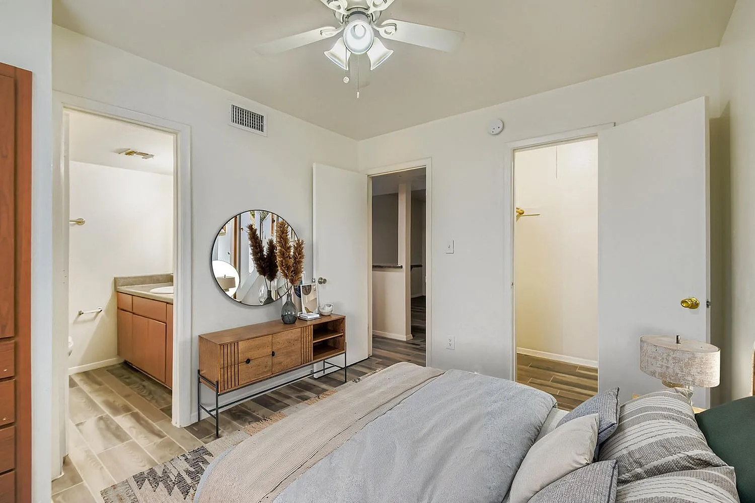 Primary bedroom, wood-style plank flooring, ceiling fan, dresser with round mirror