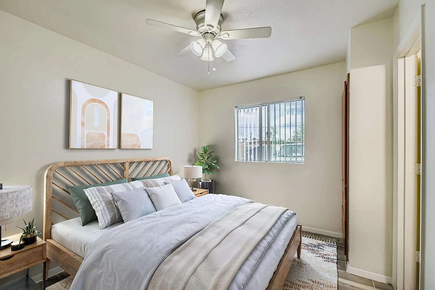 Primary bedroom, wood-style plank flooring, ceiling fan, striped bedding, rattan headboard