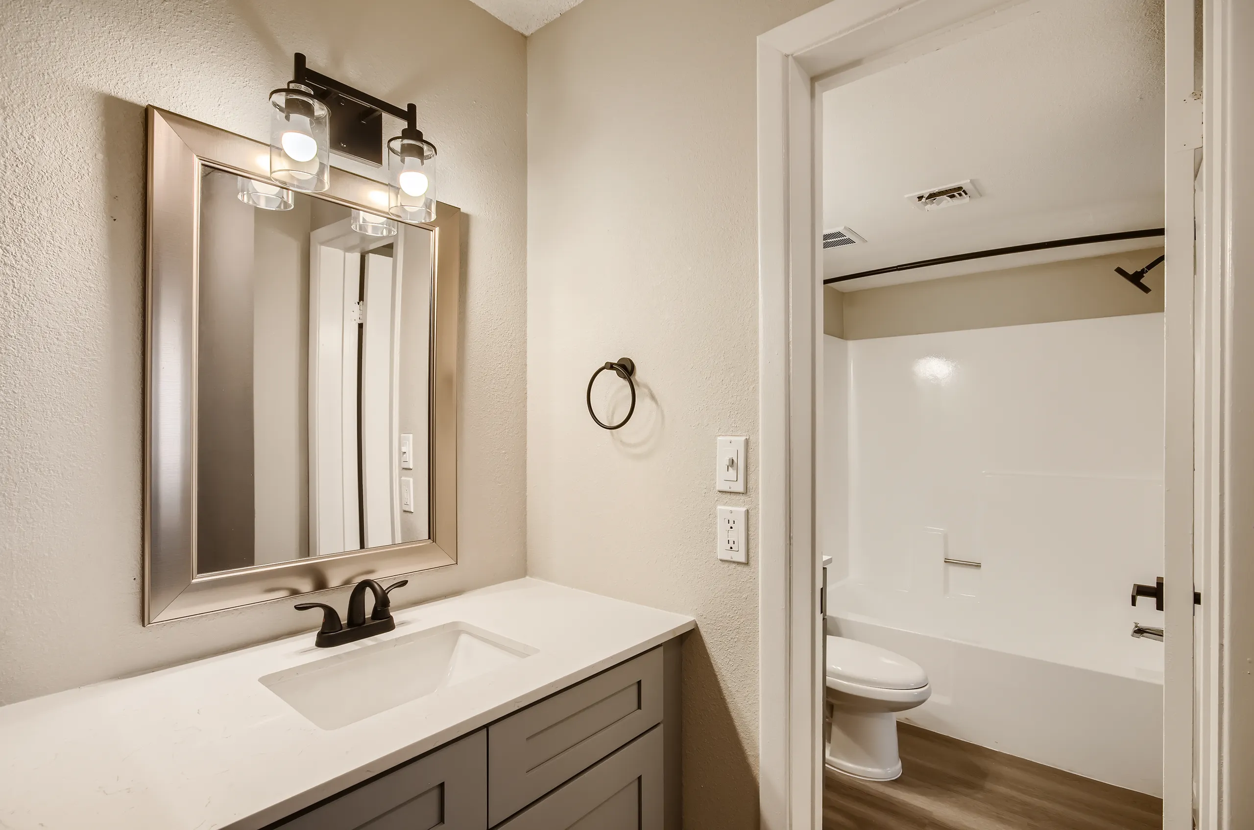 Bathroom, quartz vanity countertop, framed mirror, tub/shower combo