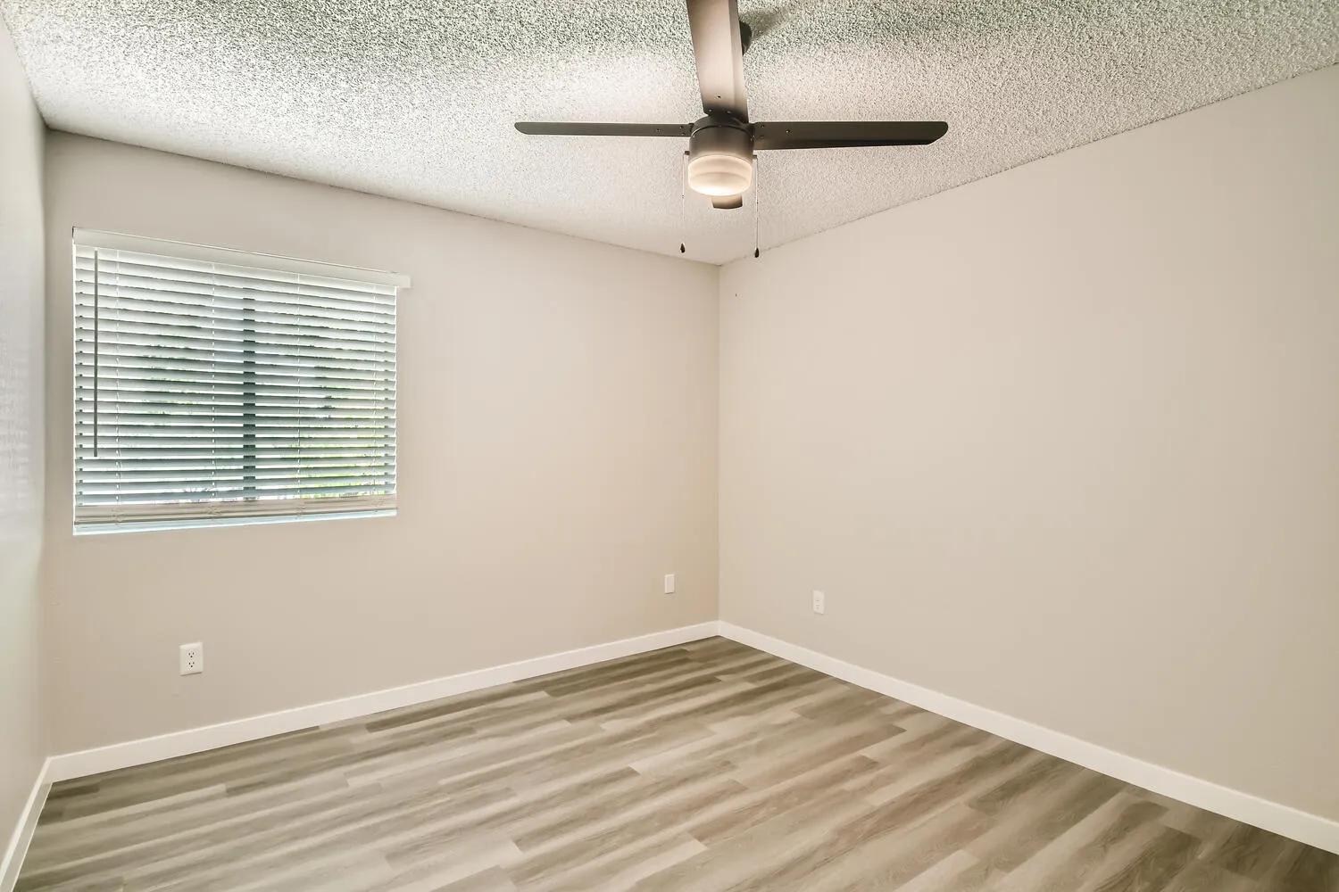 Primary bedroom, ceiling fan, mini blinds, wood-style plank flooring