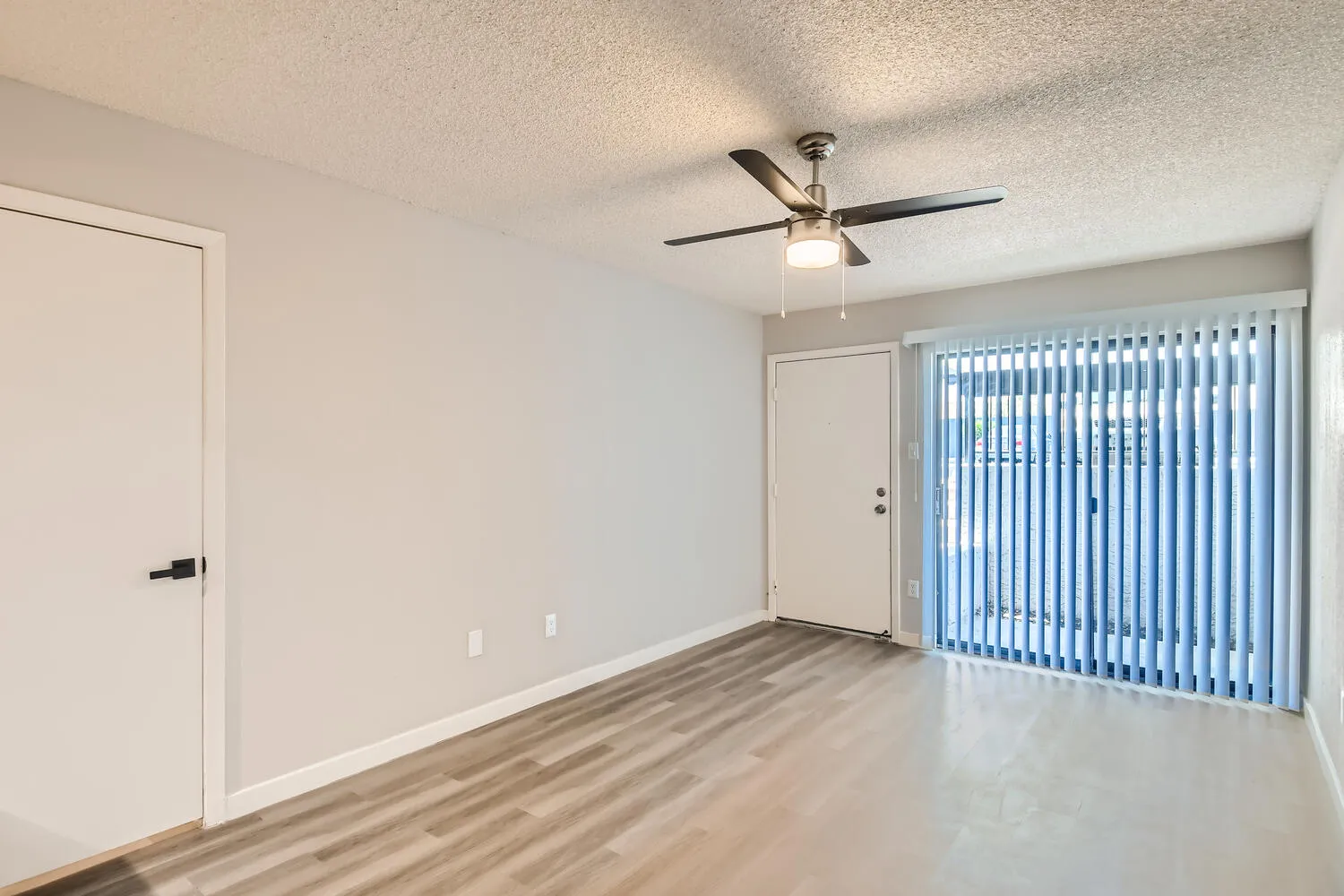 Living room, sliding glass door, vertical blinds, wood-style plank flooring