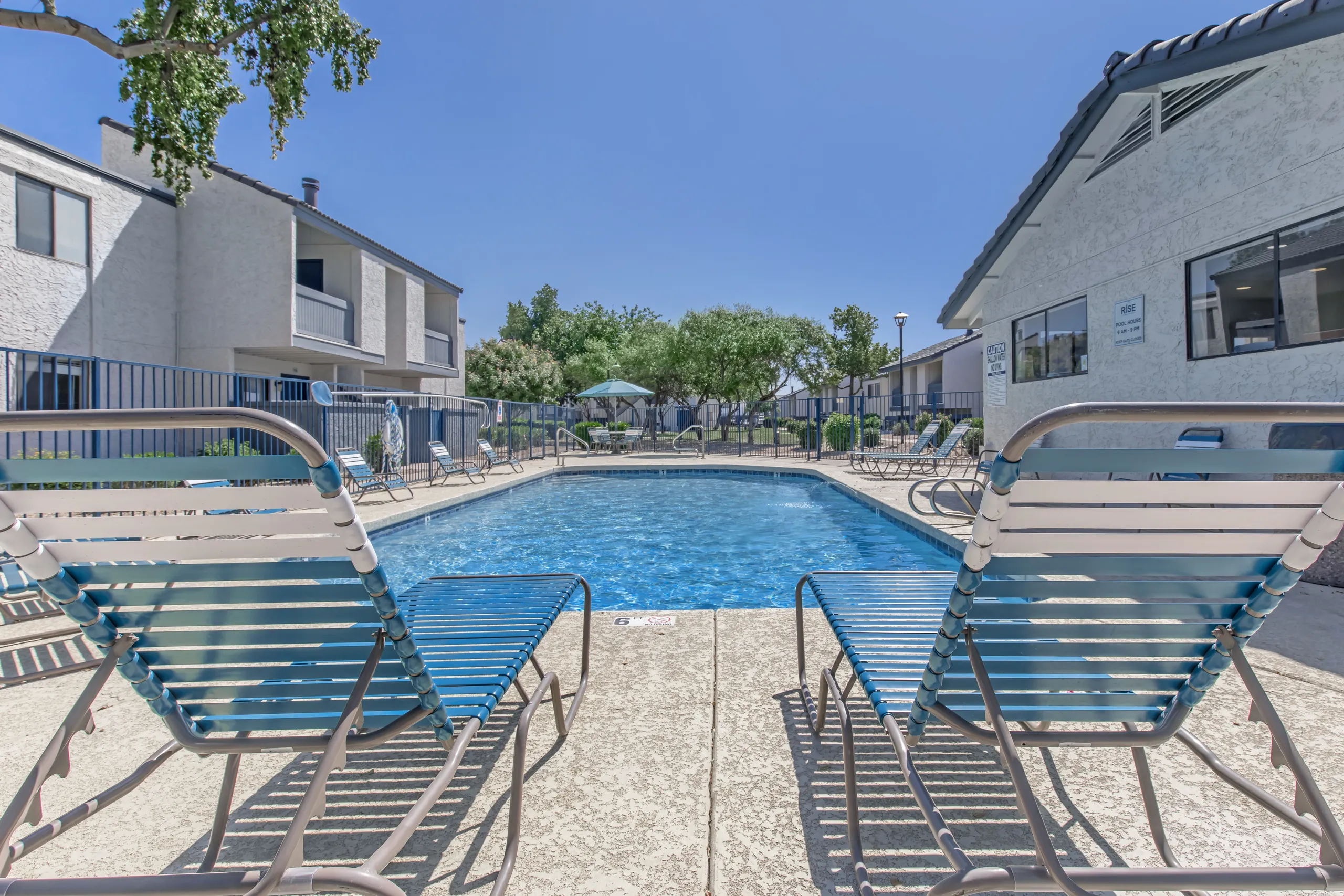 Pool with lounge seating, shaded courtyard, resident buildings in background