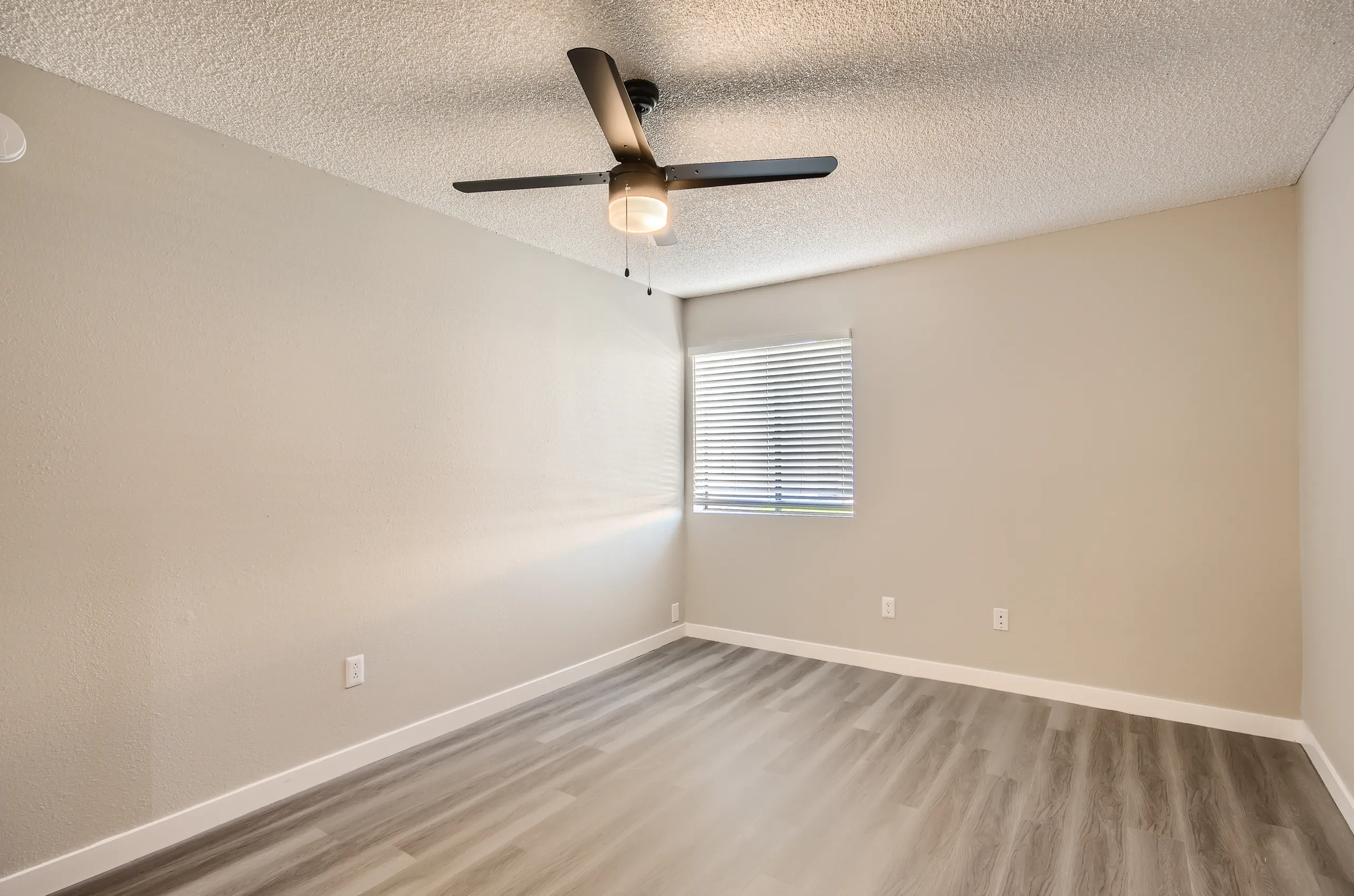Primary bedroom, ceiling fan, mini blinds, wood-style plank flooring