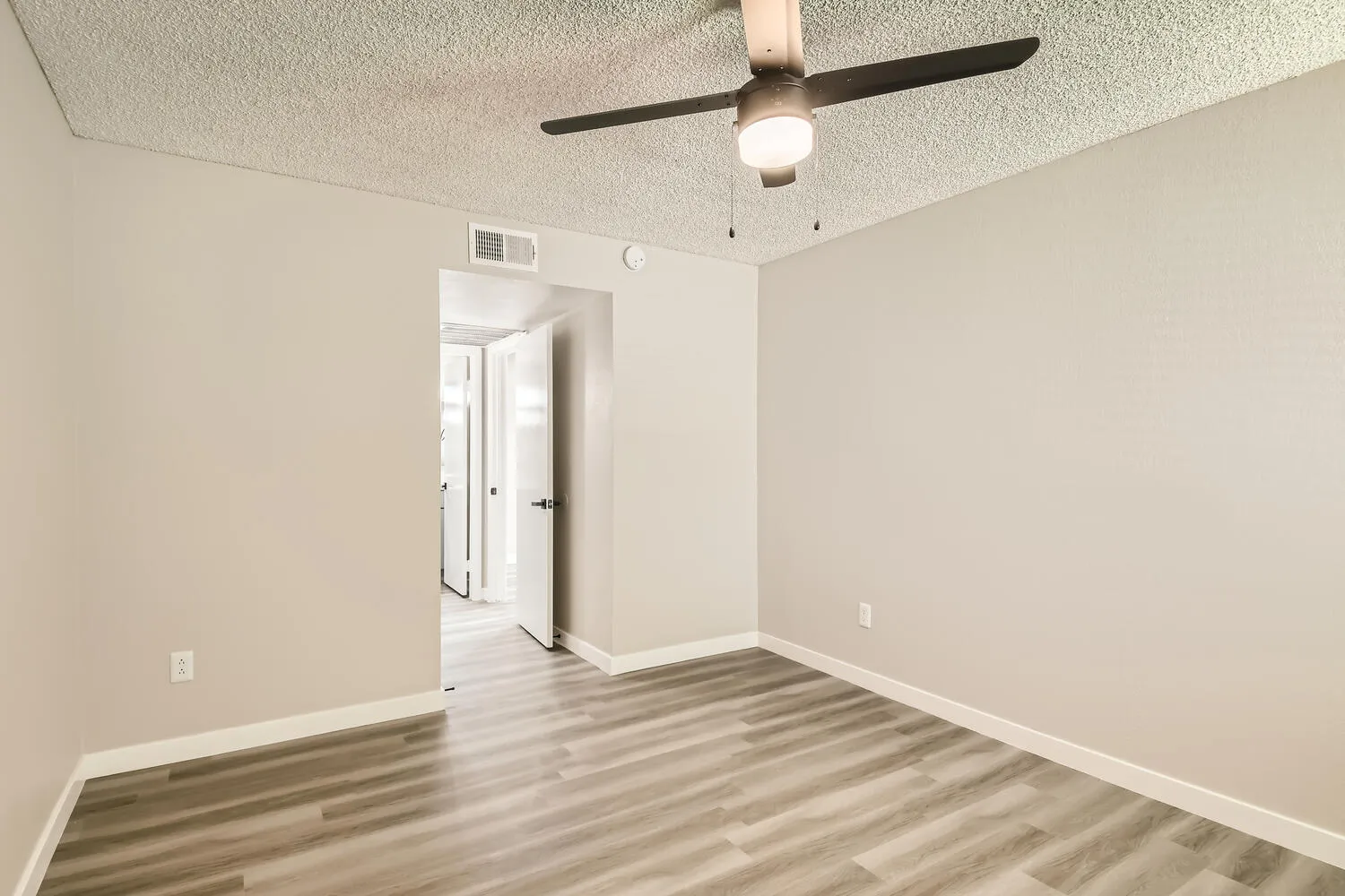 Primary bedroom, ceiling fan, hallway access, wood-style plank flooring