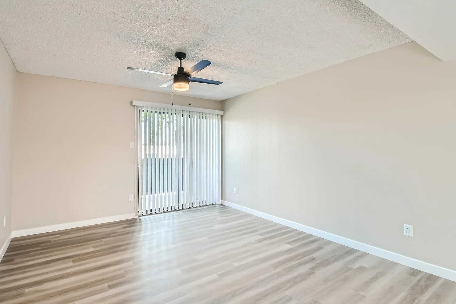 A1 Platinum living room, ceiling fan, vertical blinds, wood-style plank flooring