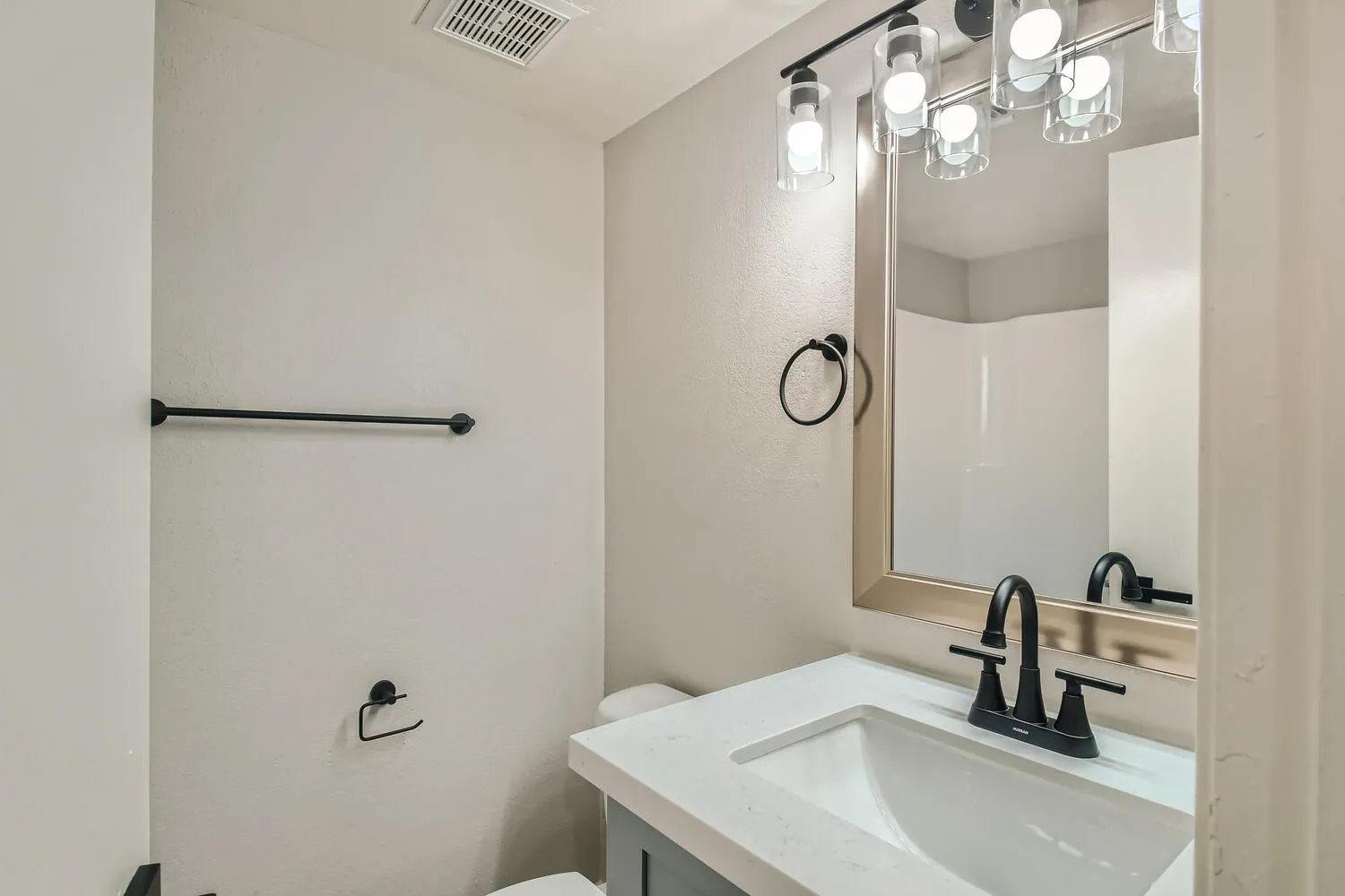 Primary bathroom vanity, quartz countertop, matte black fixtures, framed mirror