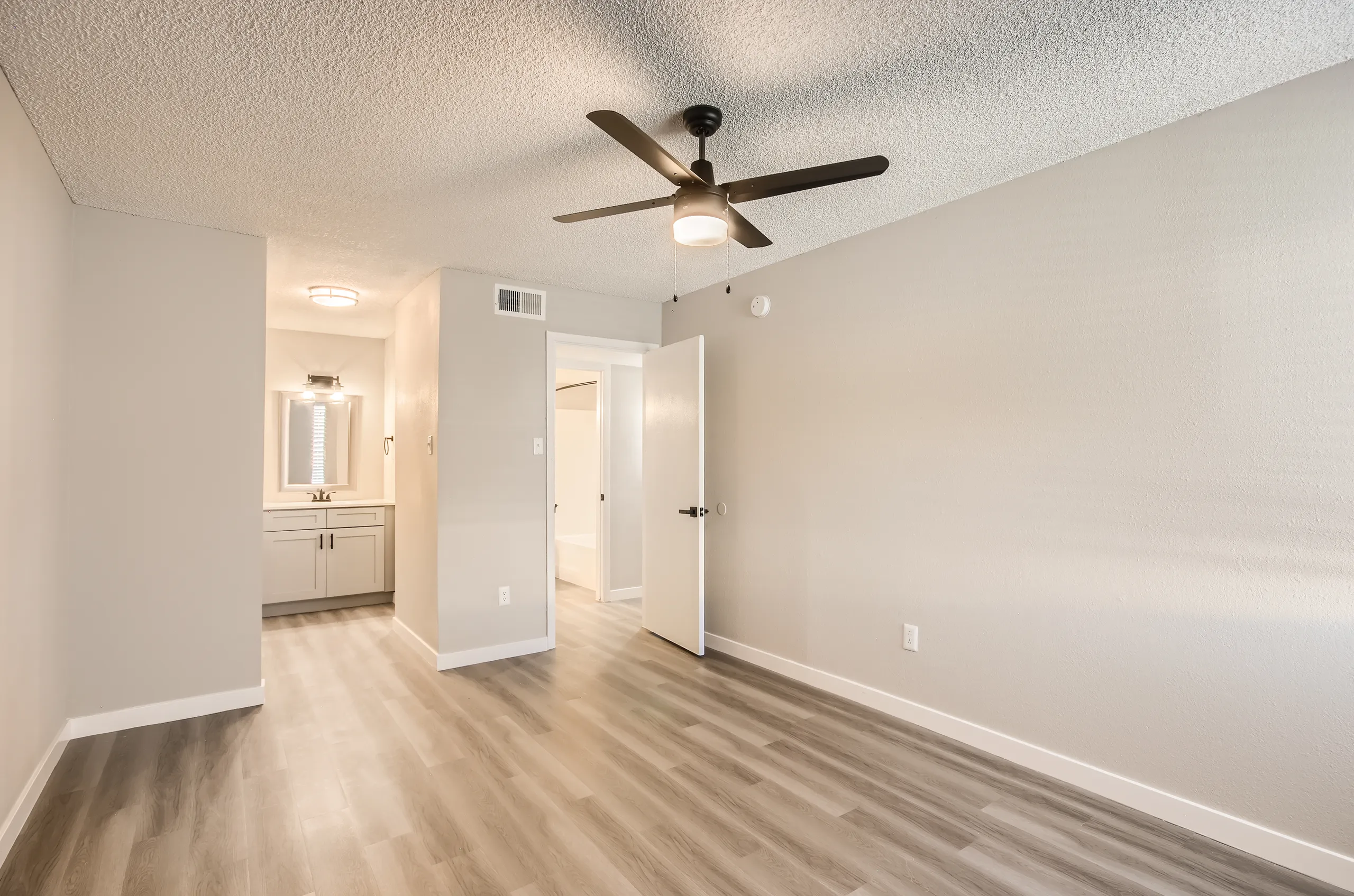 Primary bedroom, ceiling fan, bathroom access, hallway view