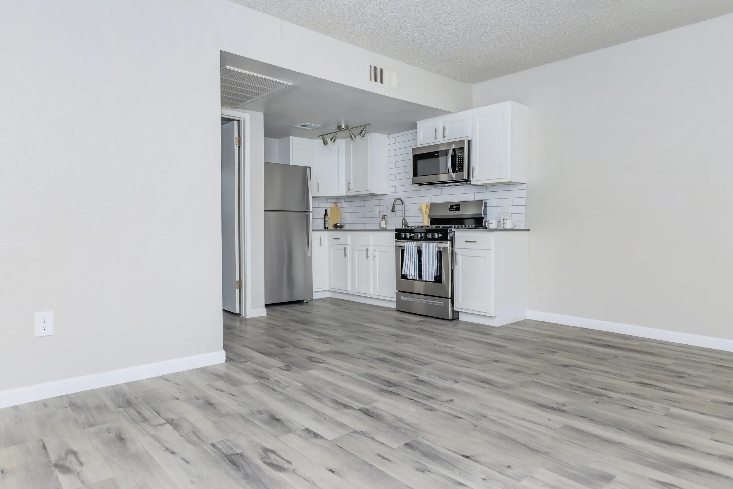 White cabinetry, stainless refrigerator and range, subway tile backsplash