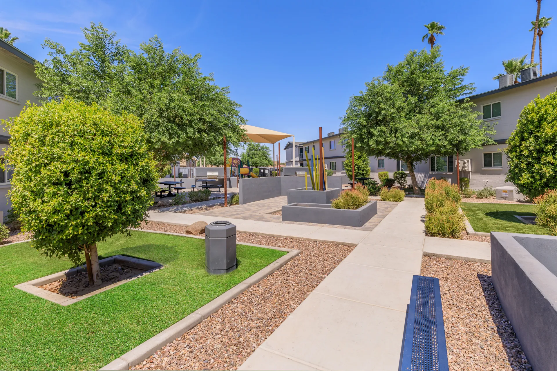 Landscaped courtyard, shaded playground structure, picnic tables, walking path