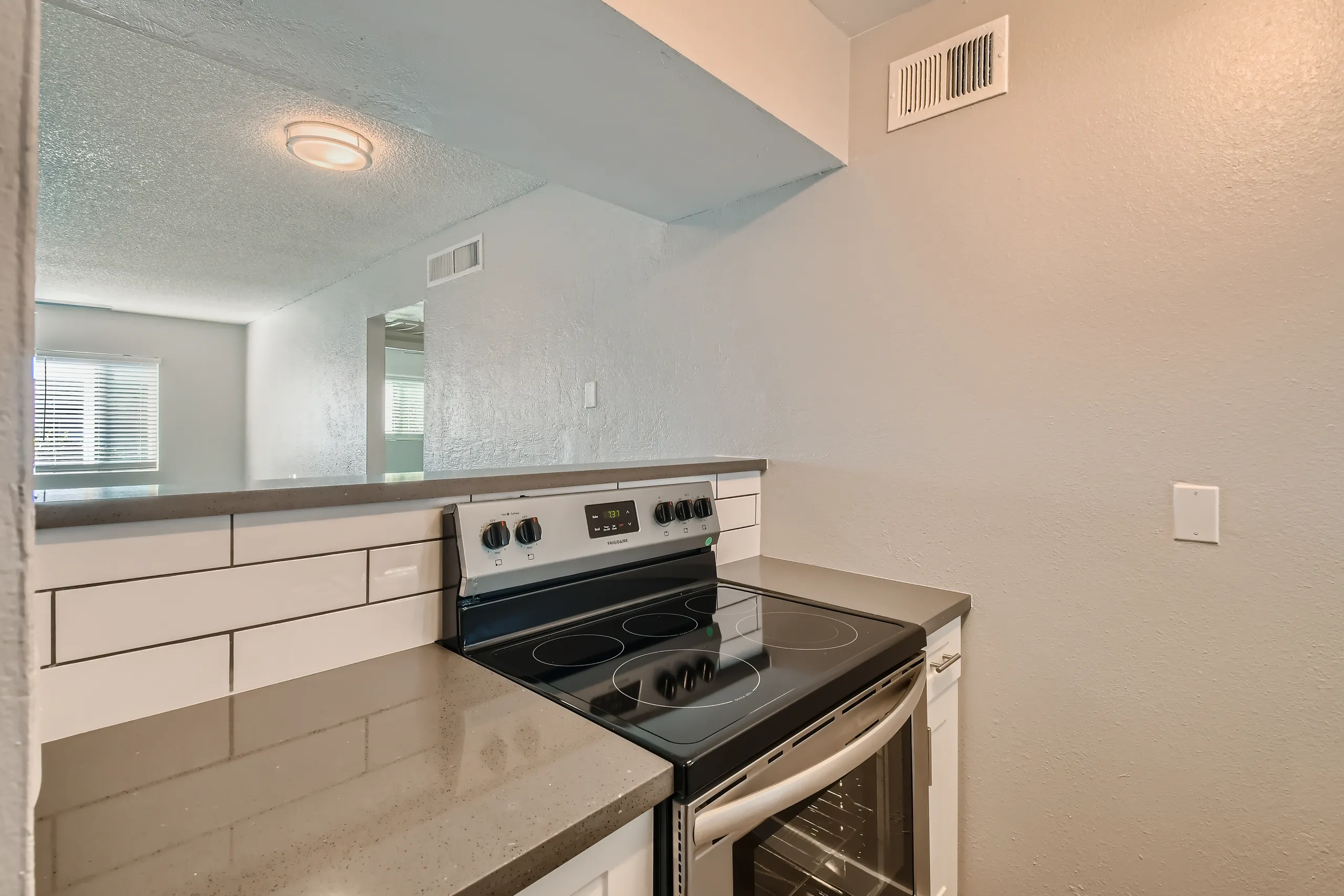 Electric range, subway tile backsplash, quartz counters, pass-through opening