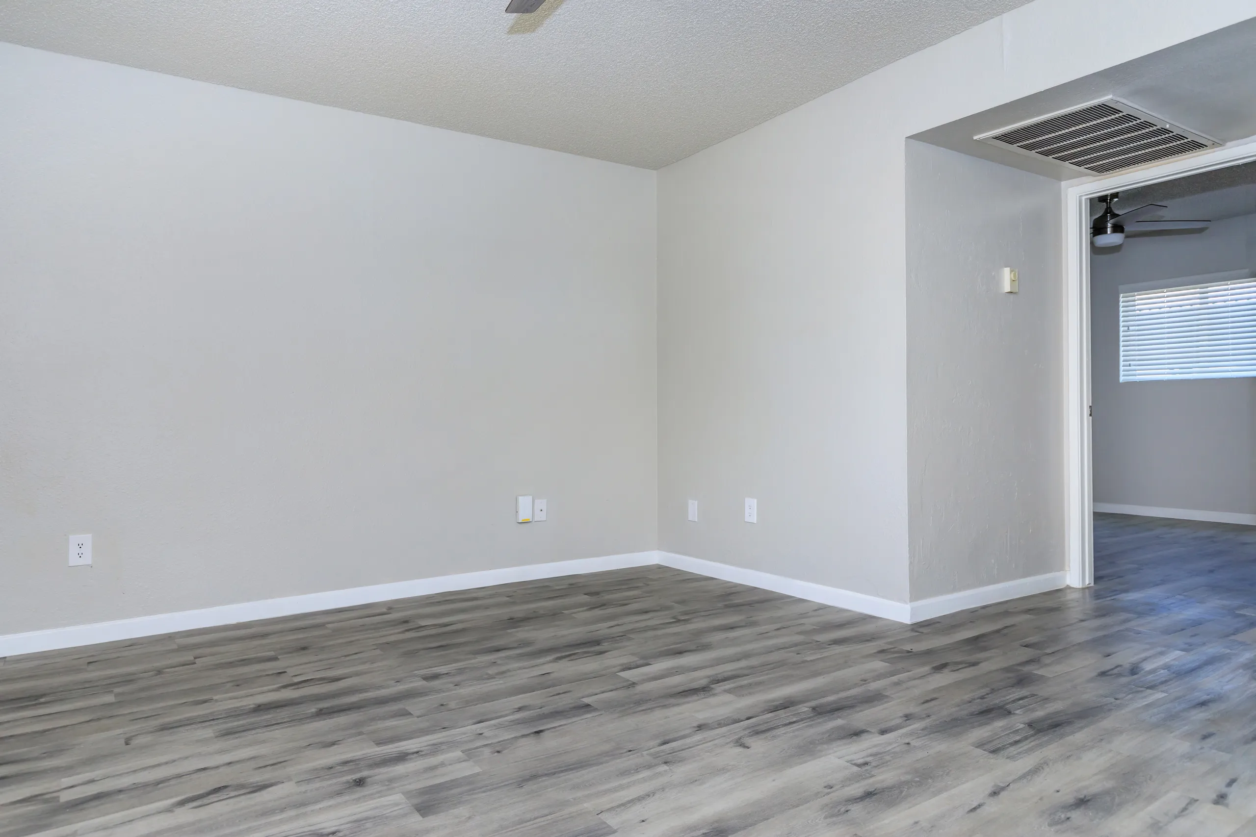 Open living area, hallway leading to kitchen, wood-style plank flooring
