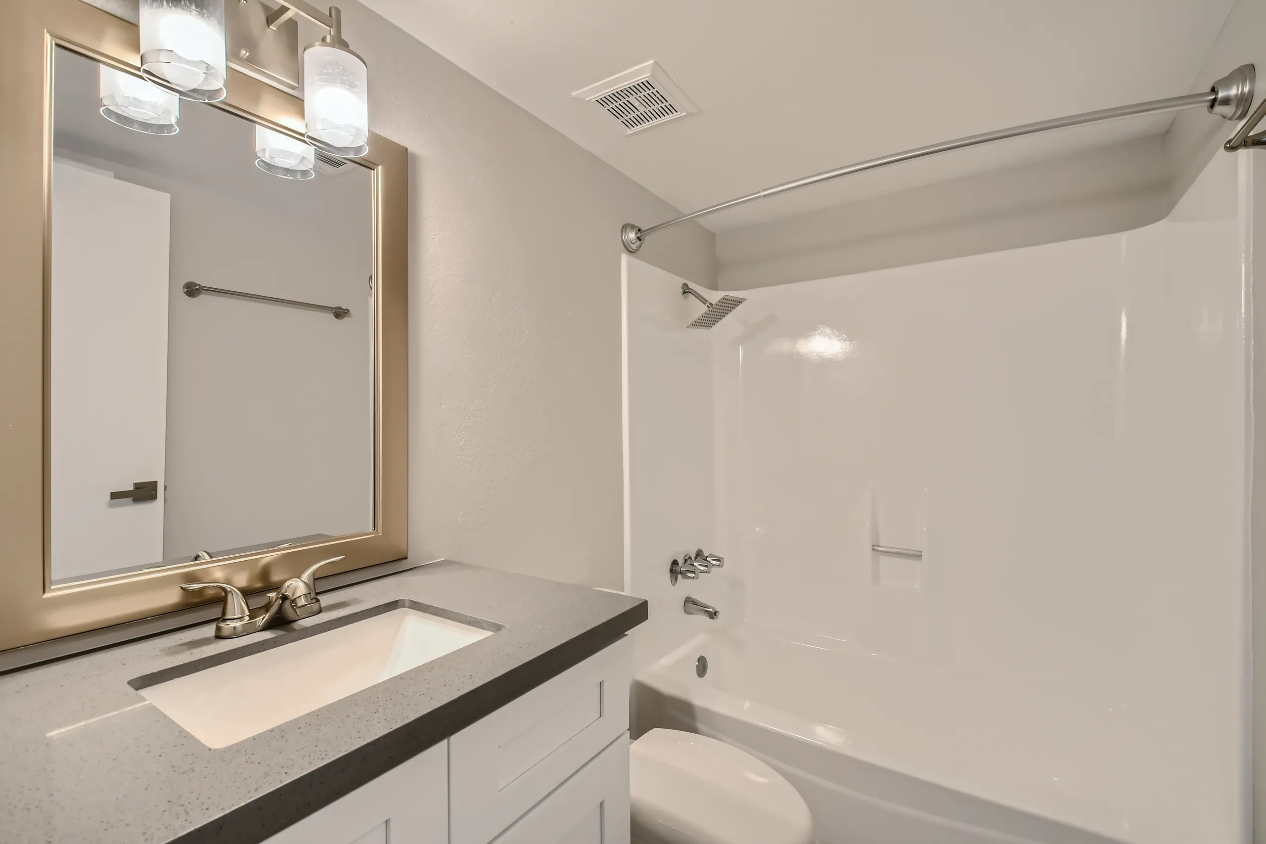Vanity with quartz counter, framed mirror, tub/shower combo
