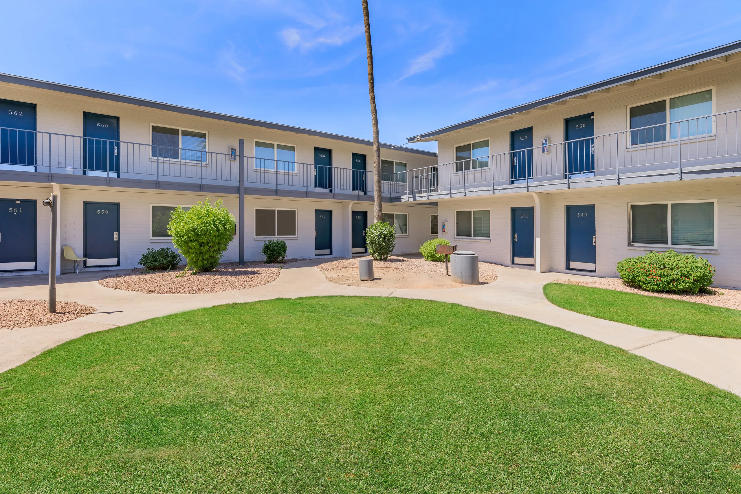 Two-story building exterior, private balconies, landscaped central lawn
