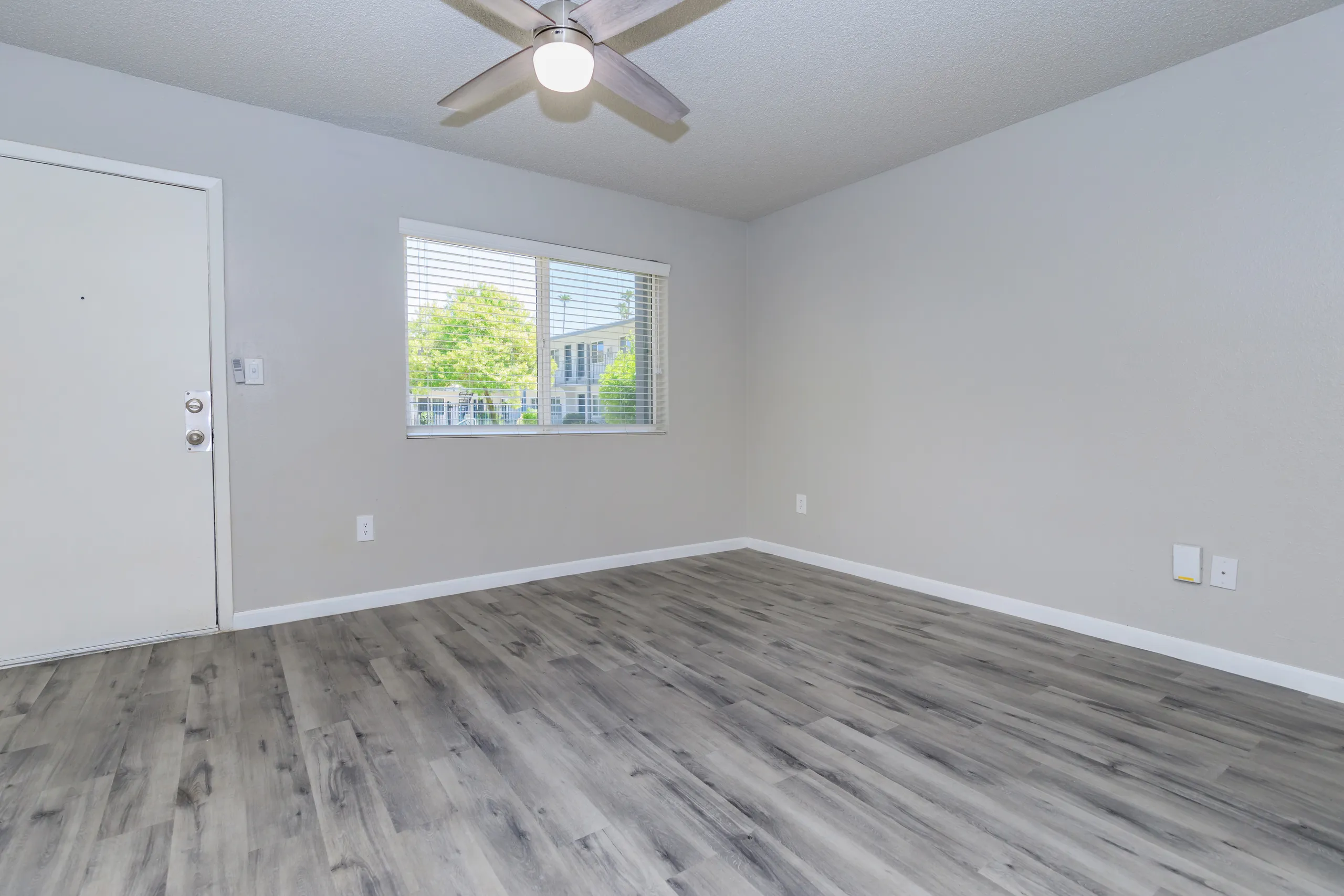 A1 Platinum living room with entry door, ceiling fan, window, wood-style plank flooring