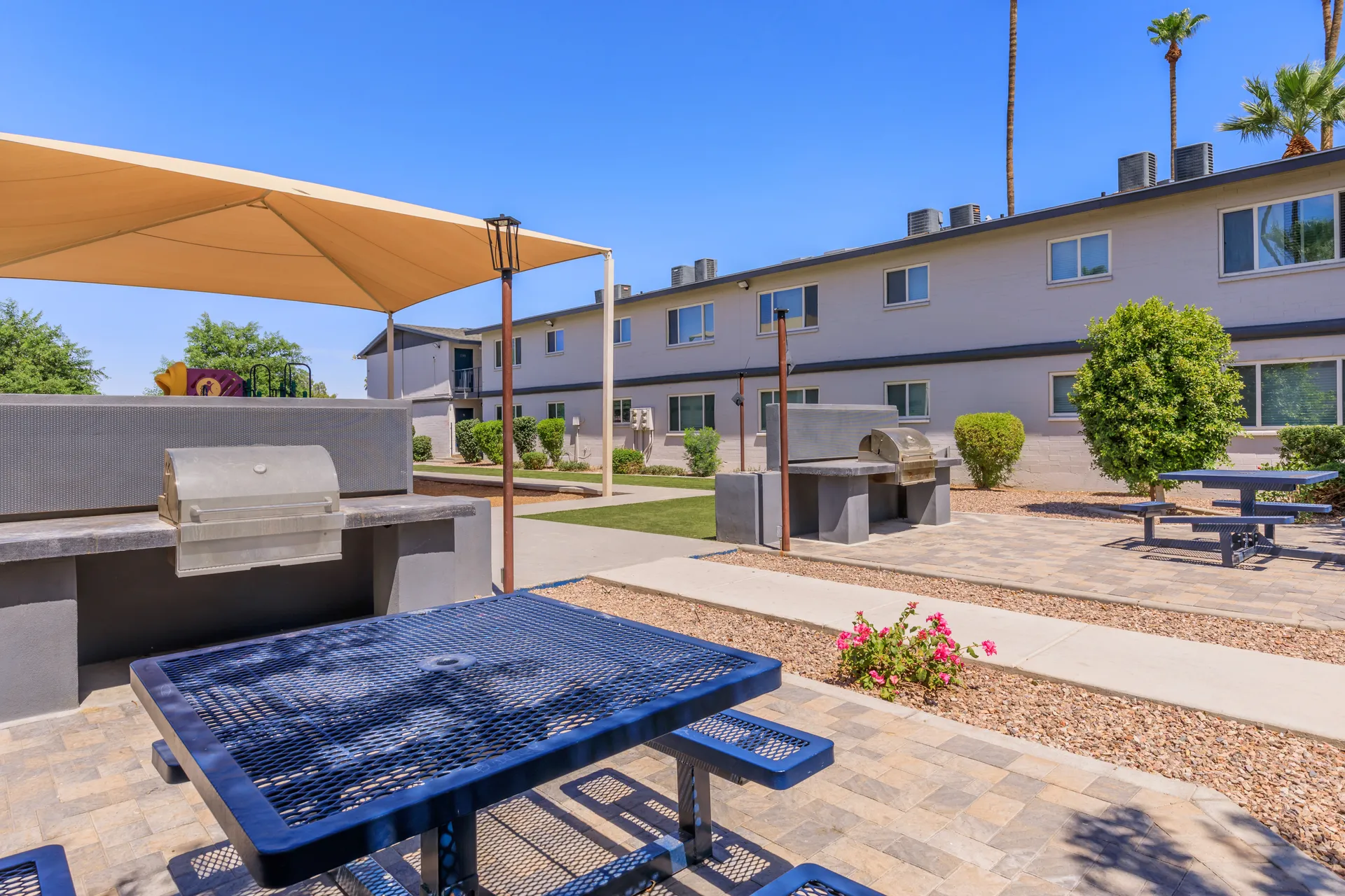 Built-in grills, shade sail, picnic table, playground in background