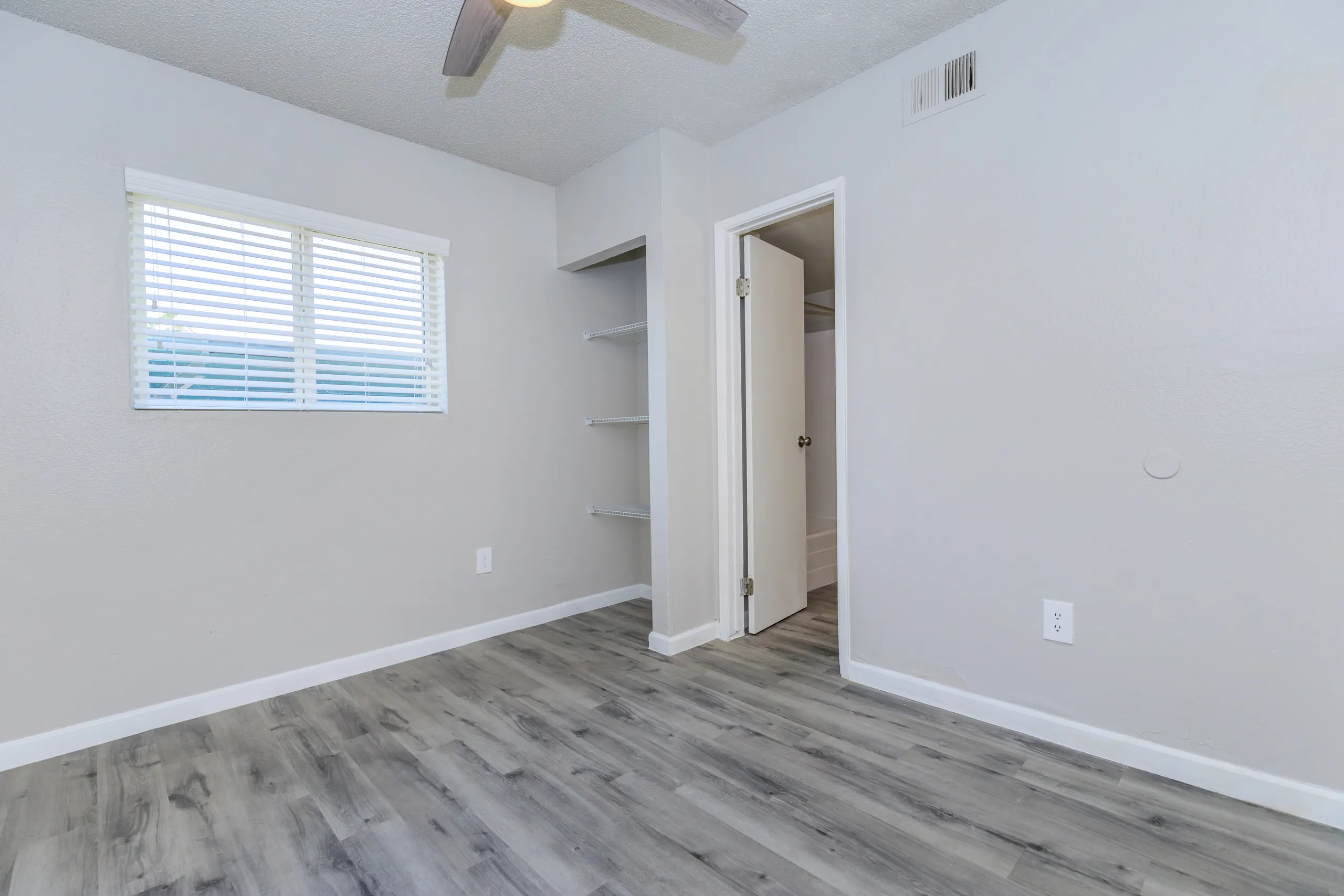 Bedroom, ceiling fan, closet with built-in shelving, wood-style plank flooring