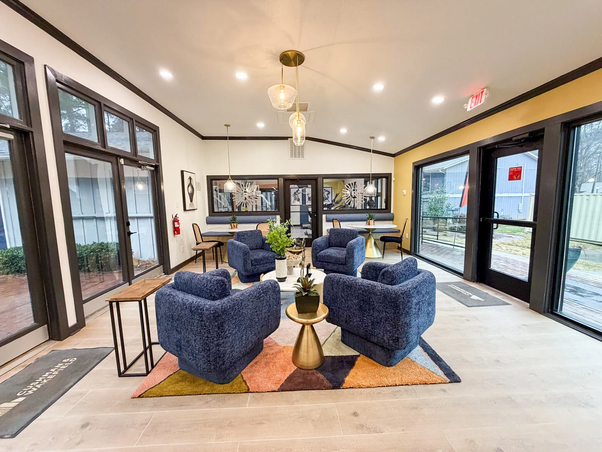 Leasing lounge, blue upholstered armchairs, wood-style plank flooring, brass accent table, pendant lighting